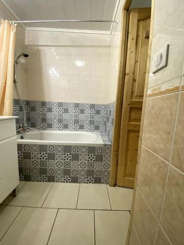 une salle de bain avec baignoire et sol carrelé dans l'établissement Appartement Station Le Corbier, à Villarembert