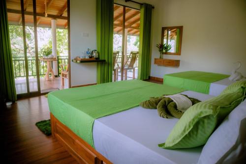 two beds in a room with green walls and windows at Evergreen Villa - Sinharaja in Deniyaya