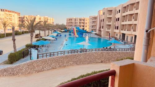 Abū ShunaynahにあるSerena north coast Al Alameinのパラソルと建物のあるスイミングプールの景色を望めます。