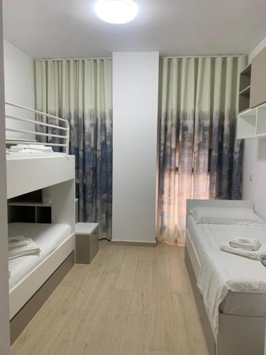 a white bedroom with two beds and a window at Luris apartament Himare in Himare