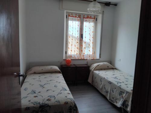 two beds in a small room with a window at Discover Appennino 15 in Montecreto