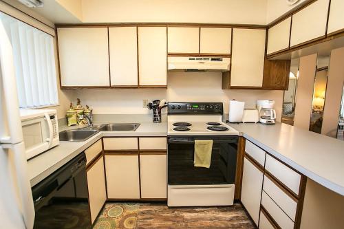 a small kitchen with a stove and a microwave at Hibiscus H204 in St. Augustine