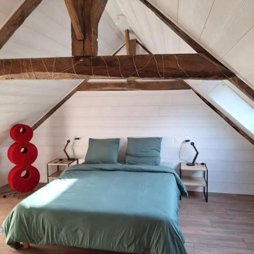 - une chambre mansardée avec un lit bleu dans l'établissement maison de caractère la petite madeleine, à Saint-Laurent