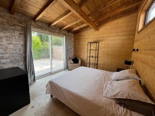 une chambre avec un lit et une grande fenêtre dans l'établissement La Maison Bois, Salavas, Vallon Pont D'Arc, à Salavas