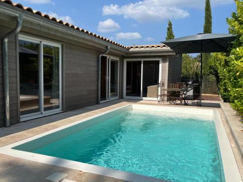 - une piscine avec un parasol à côté d'une maison dans l'établissement La Maison Bois, Salavas, Vallon Pont D'Arc, à Salavas