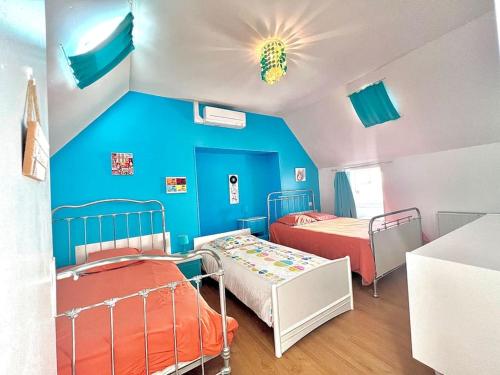 une chambre avec deux lits et un mur bleu dans l'établissement Sublime maison La mouette au coeur du Port du Guilvinec, au Guilvinec