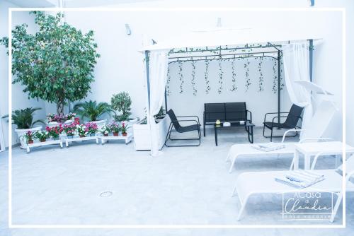 a patio with white furniture and flowers and plants at A casa di Claudia in Brindisi