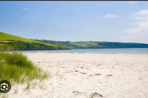 a beach with sand and a body of water at The Driftwood Den in Tywardreath