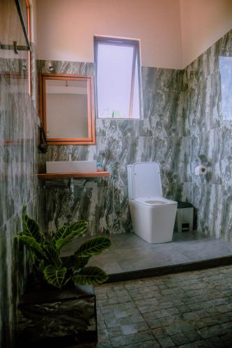 a bathroom with a toilet and a window at Evergreen Villa - Sinharaja in Deniyaya