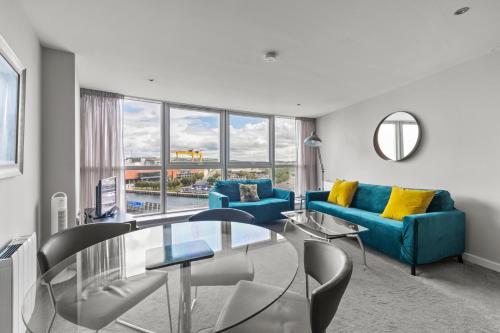 a living room with a blue couch and a glass table at Skyline Belfast in Belfast