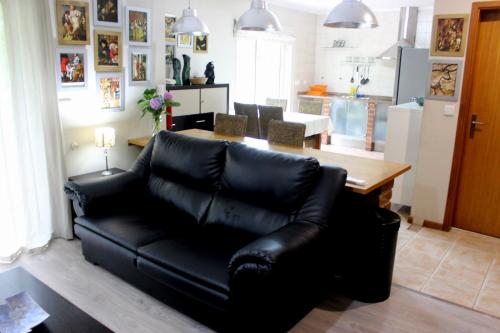 eine schwarze Ledercouch in einem Wohnzimmer mit einem Tisch in der Unterkunft Casa do Artista in Vila Verde