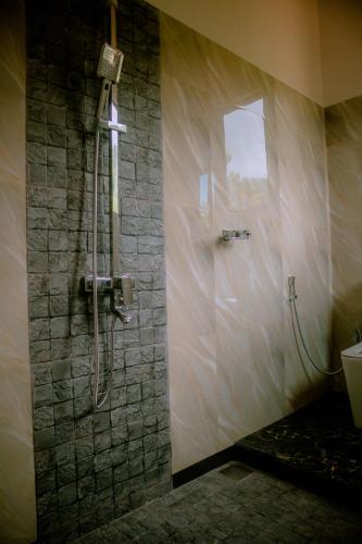 a shower in a bathroom with a stone wall at Evergreen Villa - Sinharaja in Deniyaya