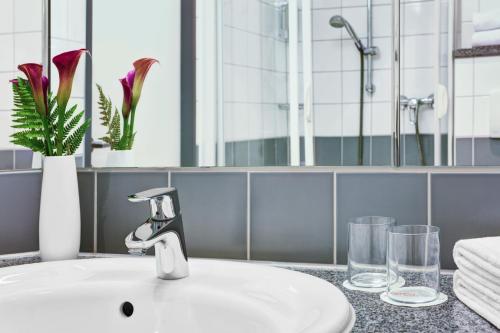 een badkamerbar met een wastafel en een spiegel bij IntercityHotel Stralsund in Stralsund