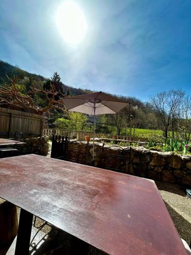 a wooden picnic table with an umbrella on top at Rives de Bourges in Burzet