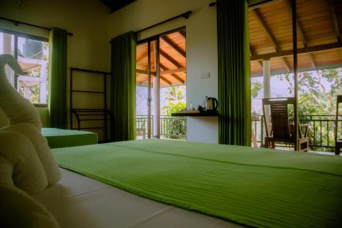 a bedroom with a green bed and a balcony at Evergreen Villa - Sinharaja in Deniyaya