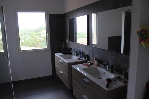 une salle de bain avec deux lavabos et un grand miroir dans l'établissement Villa ALPANNA, à Cirendinu