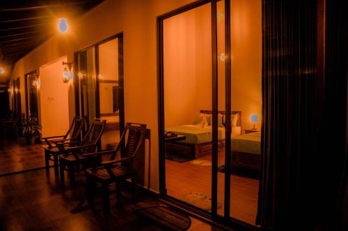 a room with chairs and a bedroom with a mirror at Evergreen Villa - Sinharaja in Deniyaya