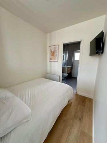 une chambre avec un lit blanc et une télévision à écran plat dans l'établissement Charmant Studio à Saint Léonard, à Angers