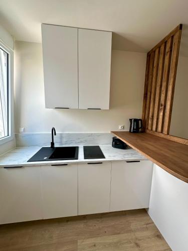 une cuisine avec des armoires blanches et un évier dans l'établissement Charmant Studio à Saint Léonard, à Angers