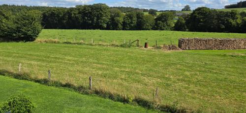 a field with a barn in the middle of it at Maison des voisins in Tavigny