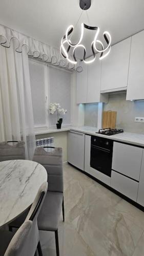 eine weiße Küche mit einem Tisch und einem Kronleuchter in der Unterkunft Квартира в Бендерах VIP in Bender