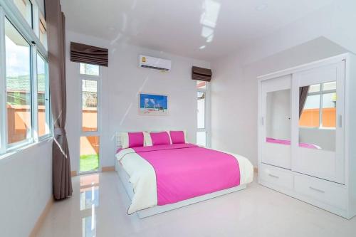 a white bedroom with a pink bed and windows at บ้านชิดหัวหินพูลวิลลา in Khao Tao