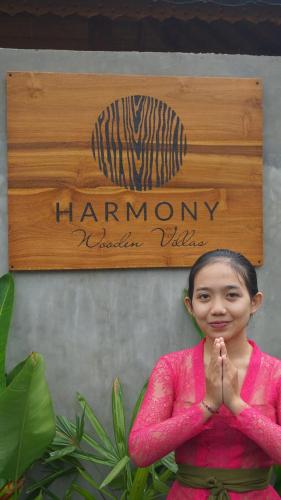 a woman in a pink shirt praying in front of a sign at Harmony Wooden Villas in Ubud