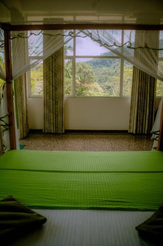 a green bed in a room with a large window at Evergreen Villa - Sinharaja in Deniyaya