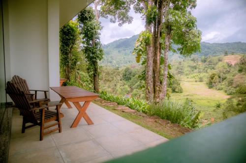 a table and chairs on a porch with a view at Evergreen Villa - Sinharaja in Deniyaya