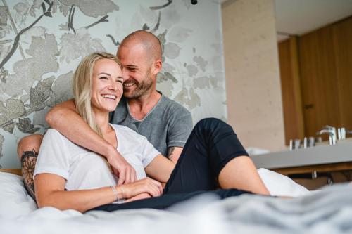 Ein Mann und eine Frau auf einem Bett in der Unterkunft Stock & Stein Lodges in Bad Gleichenberg