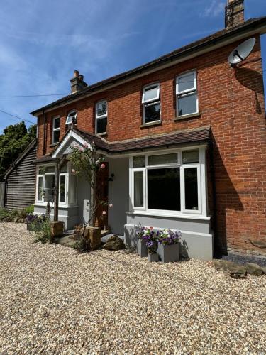 a brick house with a gravel driveway at Beulah Villa in Slinfold