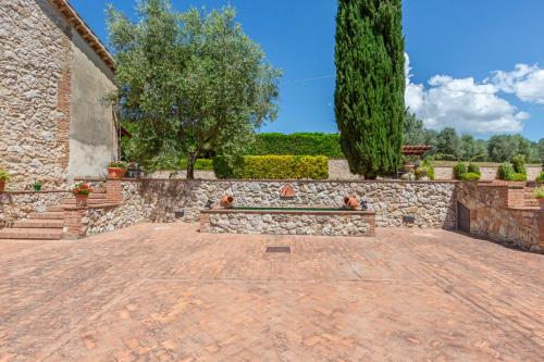 a brick courtyard with a stone wall and trees at Podere del Monte in Amelia