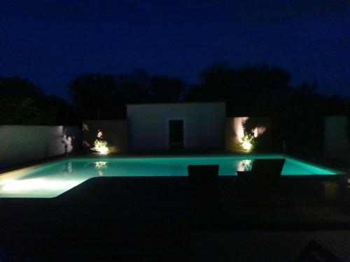 une piscine éclairée la nuit dans l'établissement L'atelier de la bergerie, à Aramon