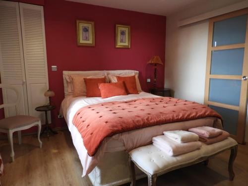 a bedroom with a large bed with red walls at AU DOMAINE DE SOPHIE Chambres d'hôtes Crasville Manche in Crasville
