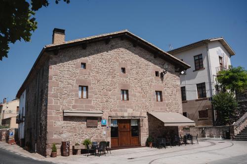 a building with tables and chairs in front of it at Hotel Rural LATORRIÉN DE ANE in Mues