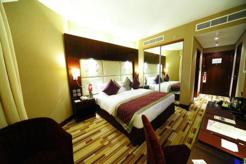 una camera d'albergo con un grande letto e una scrivania di Monaco Hotel a Dubai