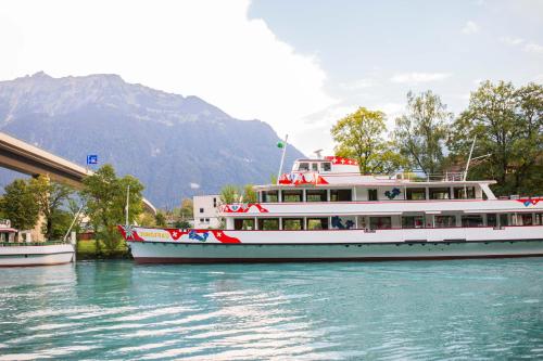 a boat on the water with a mountain in the background at Sleep and Go - Budget in Interlaken