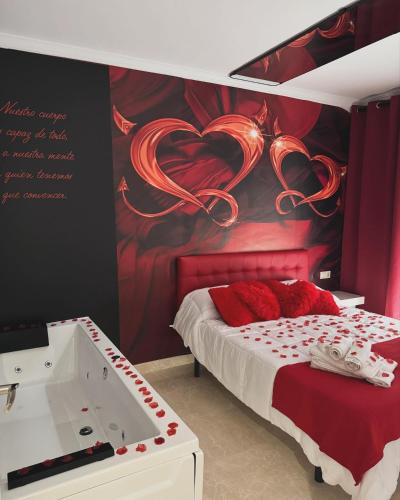 a bedroom with a bed and a bathtub with a red wall at El refugio del amor in Fuentealbilla