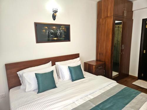 Un dormitorio con una cama con almohadas verdes y blancas. en Lake Ridge Rest, Nuwara Eliya, en Nuwara Eliya