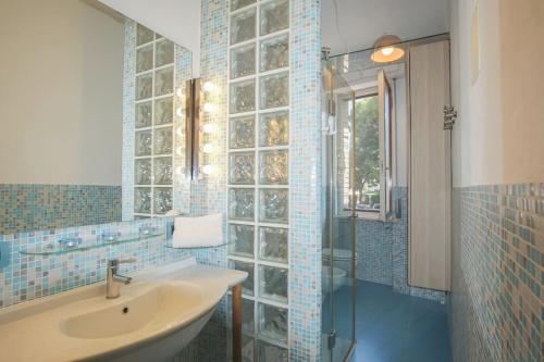 a blue tiled bathroom with a sink and a shower at Windrose Casa Cortese in Pisa