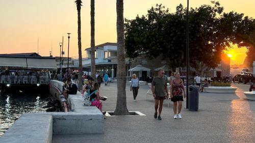 a group of people walking on a sidewalk near the water at Elysia Park Premium in Paphos City