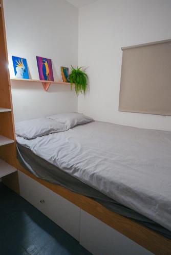 a bed in a room with a white wall at Hiška Darwin in Podčetrtek