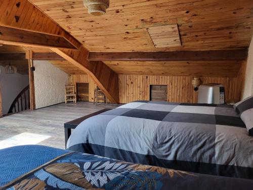 une chambre avec deux lits dans une pièce avec des plafonds en bois dans l'établissement Reposant et Dépaysant, à Lassur