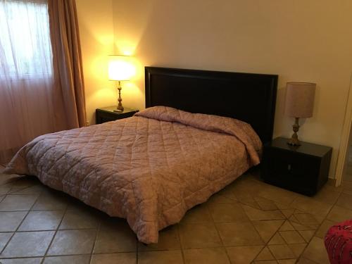 a bedroom with a large bed with two night stands and two lamps at tropical oasis in Ouakam