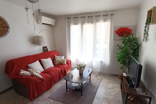 un salon avec un canapé rouge et une table dans l'établissement T3 - calme-balcon -centre-ville, à Perpignan