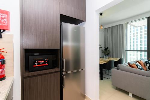 a kitchen with a stainless steel refrigerator and a living room at Elite Escape - 1 BHK Getaway Dubai Mall Access - 1509 in Dubai