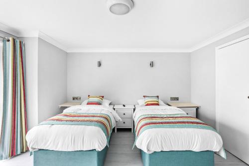 two beds in a room with white walls at Waters Edge Hotel Torquay in Torquay