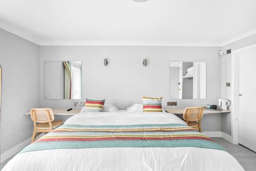 a white bedroom with a large bed and two chairs at Waters Edge Hotel Torquay in Torquay