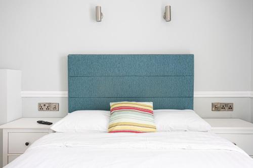 a bed with a green headboard and a colorful striped pillow at Waters Edge Hotel Torquay in Torquay
