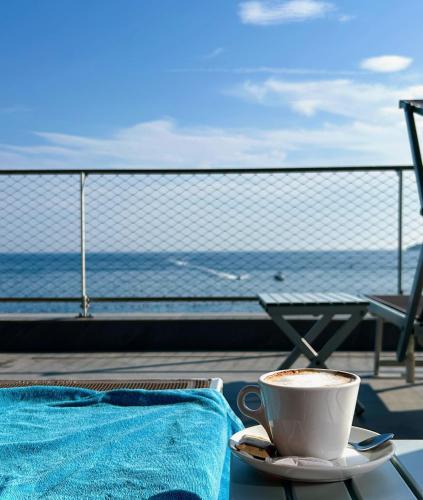 a cup of coffee sitting on a table near the ocean at Hotel Ponta Plaza Conference & Spa in Budva